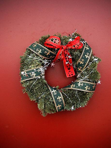 Christmas Wreath on red door A pine Christmas wreath decorated with green and red ribbon and silver stars. alintal stock pictures, royalty-free photos & images