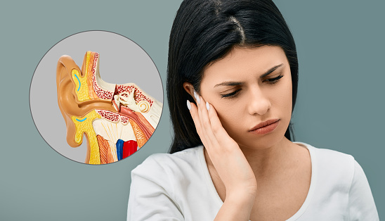 Adult woman holds hand near her ear with pain. Ear pain, earache illustration with anatomical model