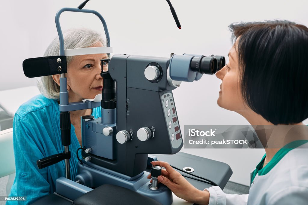 Female optometrist doing sight test to senior woman at modern ophthalmology clinic. Eye exam and vision diagnostic Eye Exam Stock Photo