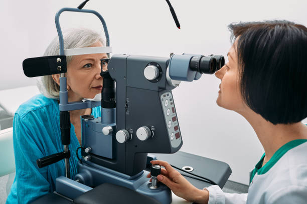optometrista feminina fazendo teste de visão para idosa na moderna clínica de oftalmologia. exame ocular e diagnóstico de visão - patient senior adult optometrist eye exam - fotografias e filmes do acervo