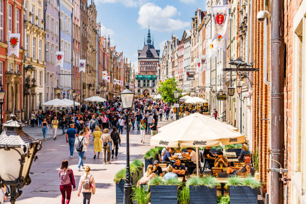 Długa street (Ulica Długa) in the centre of Gdansk old town. Old town of Gdansk, Srodmiescie historic district - crowds of tourists strolling along the Dluga street and chilling in cafes. The Golden Gate (Złota Brama) is on the background. gdansk city stock pictures, royalty-free photos & images