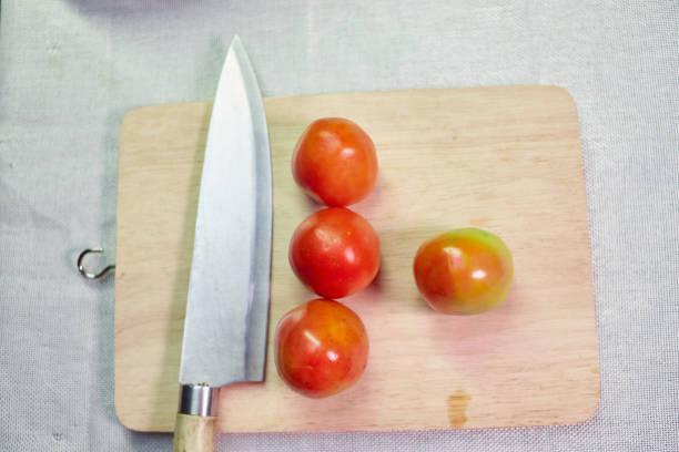 Fresh tomato with kitchen knife on cutting board