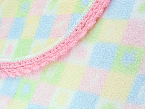 A closeup shot of a baby's blanket with a hand-crochet edging.
