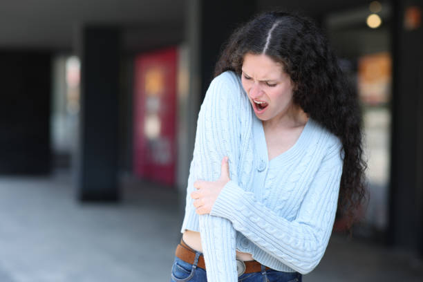 Woman suffering elbow ache in the street stock photo