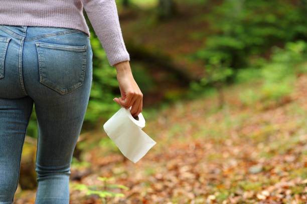 Woman walking with toilet paper in a forest stock photo