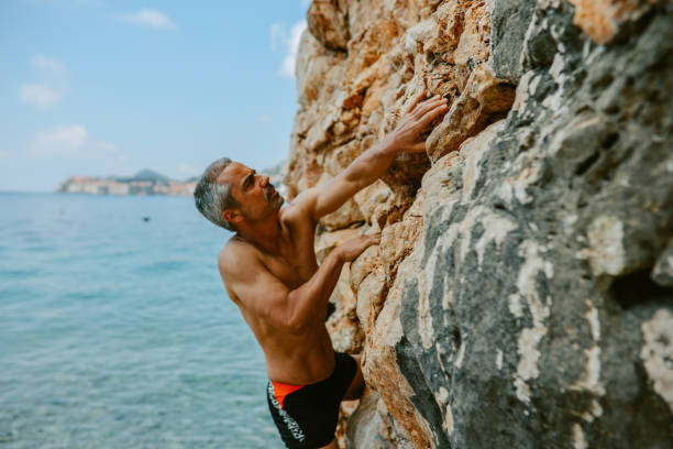 Mid aged man doing a free climbing session at the Croatian seaside.