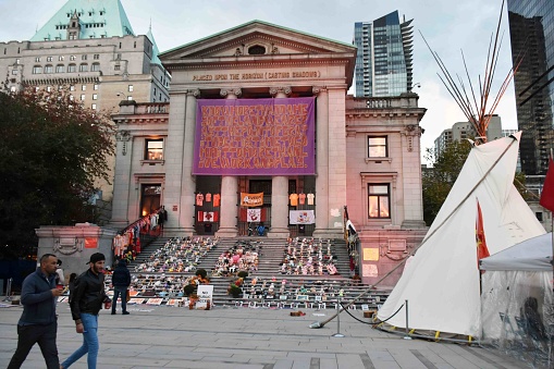 Scene Of Canadian Indigenous Huts, Vancouver Art Gallery In British Columbia Canada, People, Children's Boots And Shoes On The Ground As A Memorial For All The Dead first Nations Children