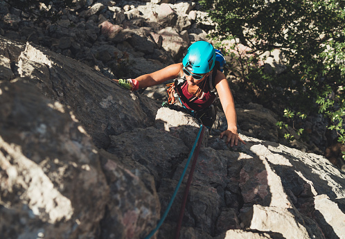 Active Woman in protective helmet and sunglasses on cliff rock wall lead climbing using rope and climbing harness in Paklenica National park, Croatia. Active extreme sports time spending concept photo