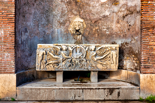 Fountain composed of a lion's head and an ancient Roman sarcophagus in Piazza del Colosseo, Rome Italy