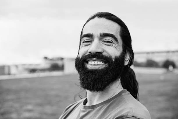 Young happy man looking at camera outdoor - Focus on face - Black and white editing