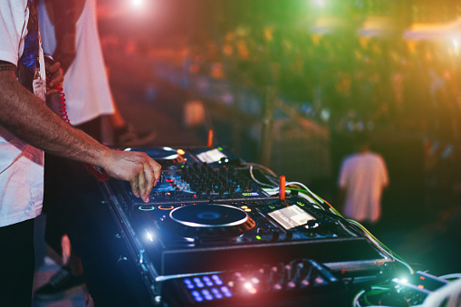 Dj mixing at beach night party during summer vacation outdoor - Focus on hand