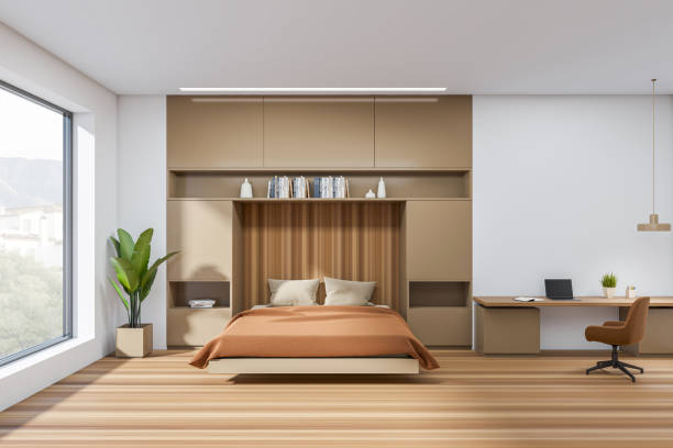 istock Bedroom interior with bed and workplace with laptop, window on countryside 1402647309