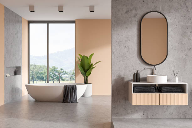 istock Bright beige and concrete bathroom interior with sink, bathtub and panoramic window 1402648258