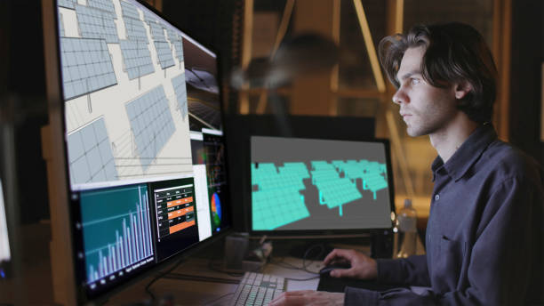 CAD solar panel array. Close up stock image of a bearded young man working at a computer screen. He’s working on CAD software looking at the design of a solar panel array in CAD with data. computer aided design stock pictures, royalty-free photos & images