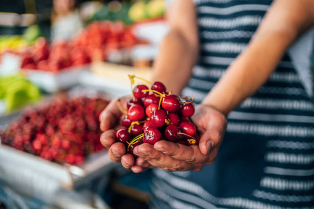 Male market vendor showing cherries to a customer of his market stall