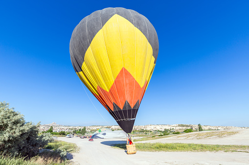 A woman travels through Cappadocia at the background of a grandiose balloon show in Turkey