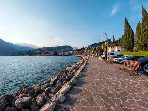 Tarbole, Italy - May, 2022 : Lakeside of the Lake Garda, walking path from Tarbole to Riva del Garda, with mountains on the background