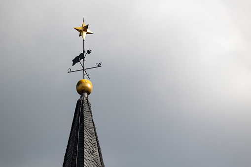 Friedrichsdorf, Hochtaunus, Hessen, Germany Mai 2022. Spire of the church tower of the Protestant church in Friedrichsdorf. Golden ball and star on the top.