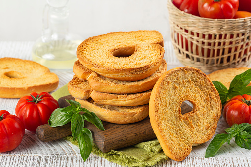 Friselle or frese, a type of twice-baked bagel shaped bread from Puglia, Italy. Ingredients, tomatoes, basil, olive oil.