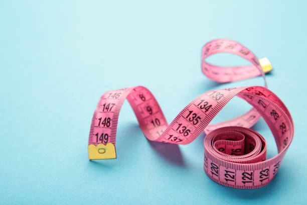 istock Pink plastic measure tape with metric scale over on blue background. 1402652138