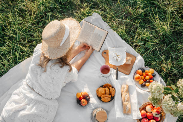 istock Woman read book on picnic in field. 1402653275