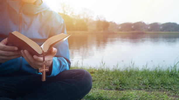 uomo che legge la bibbia sul lago al mattino - christianity foto e immagini stock