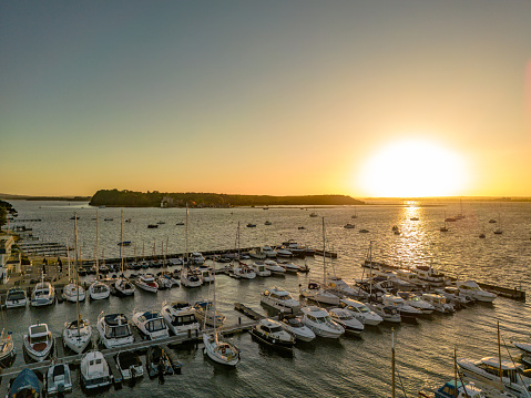 Poole, UK. Sunday 12 June 2022. Sunset over Brownsea Island with Sandbanks Marina in Poole Harbour.