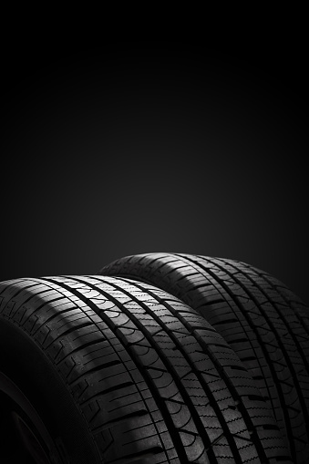 New car tires on black background with copy space. Vertical image.