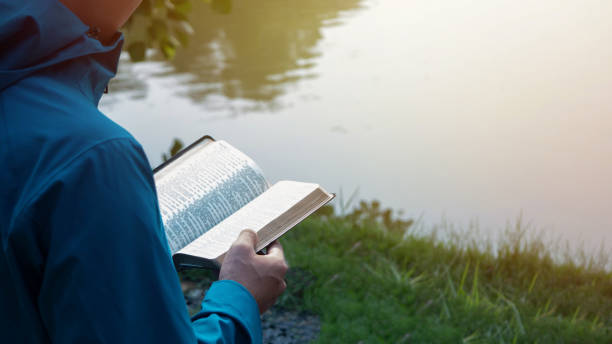 istock Man Reading Bible By Lake 1402654181