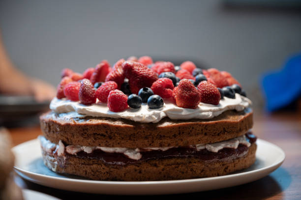 Delicious homemade vegan cake topped and decorated with cream and berry fruits stock photo