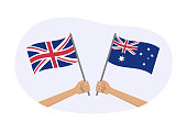 istock UK and Australia flags. Australian and British national symbols. Hand holding waving flag. Vector illustration. 1402655581