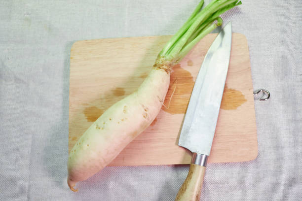 istock Fresh daikon radishes with kitchen knife on cutting board 1402657412