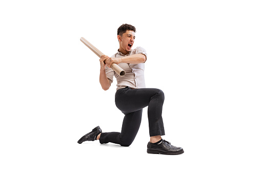 Portrait of young emotive man, employee with cardboard tube isolated over white studio background. Removing obstacles and troubles. Concept of business, promotion, growth, success, challenge