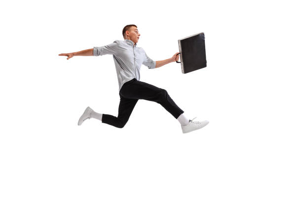 istock Portrait of young man. office worker jumping over obstacle with suitcase isolated over white studio background. 1402658577