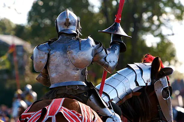 A jousting knight in metal armor shown from the back