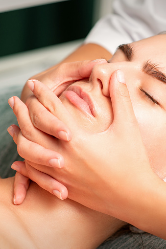 A young caucasian woman getting facial massage in a spa