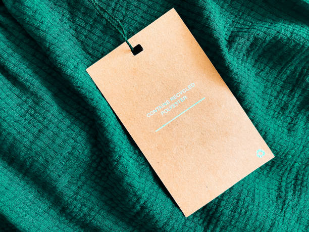 contient une étiquette d’étiquette de mode en polyester recyclé, une carte de prix de vente sur fond de tissu vert émeraude de luxe, des achats et des magasins de détail - polyester photos et images de collection