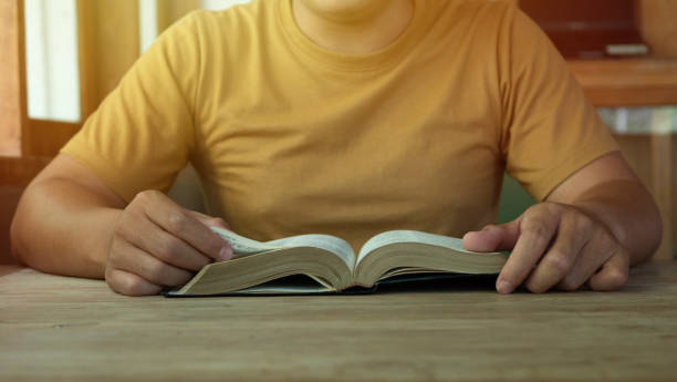 istock A man holding and read bible on wood table with window light, crisis solution pray to God, Christian believe, trust and obey , morning devotional concept with copy space 1402663405
