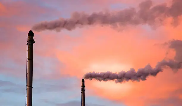 Industrial chimneys with smoke emissions (pink sunset background)