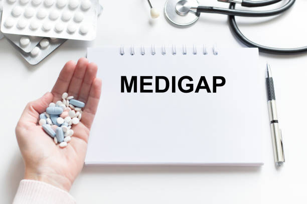 Medigap word on notebook on doctor's desk next to hand with tablets, medical concept Medigap word on notebook on doctor's desk next to hand with tablets, medical concept medigap stock pictures, royalty-free photos & images