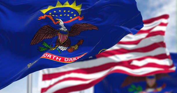 The North Dakota state flag waving along with the national flag of the United States of America The North Dakota state flag waving along with the national flag of the United States of America. In the background there is a clear sky. North Dakota is a U.S. state in the Upper Midwest north dakota stock pictures, royalty-free photos & images