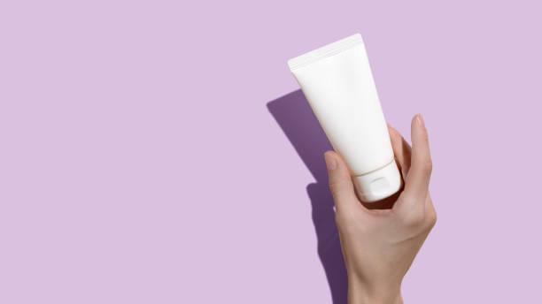 istock Young female hands holding blank white squeeze bottle plastic tube on pink background. Packaging of cream, lotion, gel, facial foam or skincare. Cosmetic beauty product branding mock-up. Copy space 1402667343