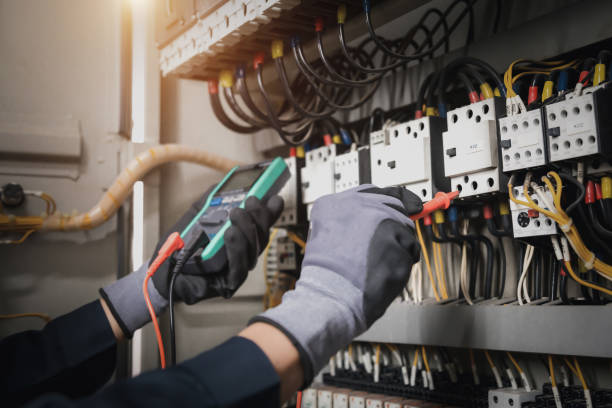 istock Electricity and electrical maintenance service, Engineer hand holding AC multimeter checking electric current voltage at circuit breaker terminal and cable wiring main power distribution board. 1402667935