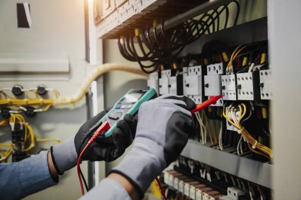 serviço de eletricidade e manutenção elétrica, engenheiro segurando manualmente ac multimetrômetro verificando tensão de corrente elétrica no terminal do disjuntor e placa de distribuição de energia da fiação do cabo. - electricity control panel engineer electronics industry - fotografias e filmes do acervo