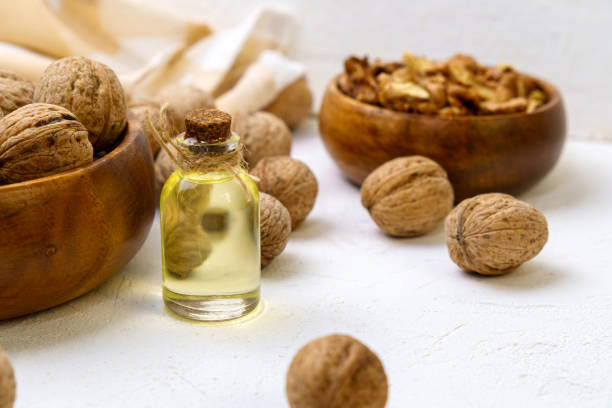 istock Glass bottle with essence, raw walnut peeled and in their shells, rustic style, selective focus 1402674029