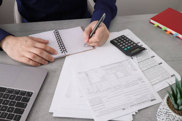 istock Businessman sitting at a table in office writing notes down on a spiral notepad. 1402674591