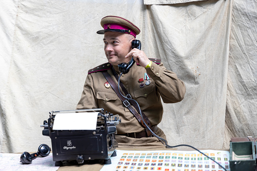 Moscow, Russia - June, 10,2022: Boulevard Ring. Festival of Times and Epochs. A male reenactor in the role of a signalman talks on a military phone