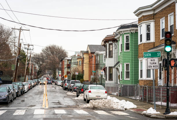 Parked cars and light traffic on a residential street in Boston, with some snow still lying on the street during March.