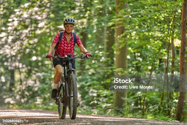 Senior Woman On Electric Mountain Bike In Green Forest Stock Photo - Download Image Now