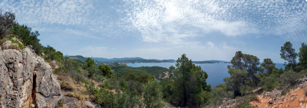 Viewpoint of the Majorca coastline with the view on the sea, cliffs, forest and summer sky, Mallorca, Balearic islands, Spain Panoramic view of the Majorca coast with the view on the sea, cliffs, forest and summer sky, Mallorca, Balearic islands, Spain, Europe seaside views of cala fornells mallorca stock pictures, royalty-free photos & images